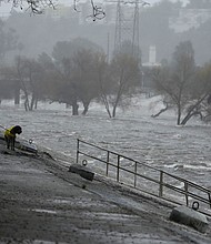 A man walks his dog on the edge of the Los Angeles River, carrying stormwater downstream on February 4 in Los Angeles. The second of back-to-back atmospheric rivers battered California, flooding roadways and knocking out power to hundreds of thousands.
Mandatory Credit:	Damian Dovarganes/AP