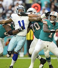 Miami Dolphins quarterback Tua Tagovailoa stands back to pass as Dallas Cowboys linebacker Micah Parsons is held back by Miami's offensive line on Christmas Eve 2023.
Mandatory Credit:	Rebecca Blackwell/AP