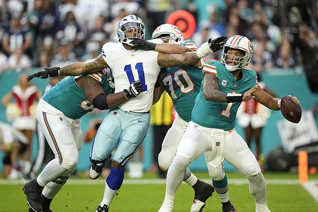 Miami Dolphins quarterback Tua Tagovailoa stands back to pass as Dallas Cowboys linebacker Micah Parsons is held back by Miami's offensive line on Christmas Eve 2023.
Mandatory Credit:	Rebecca Blackwell/AP