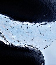 A scientist holds a piece of ice core drilled from West Antarctica, showing the air bubbles trapped within.
Mandatory Credit:	University of Cambridge/British Antarctic Survey