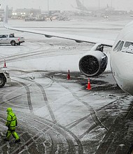 A man walks near a waiting plane as snow falls at John F. Kennedy International Airport in New York on Tuesday.
Mandatory Credit:	Frank Franklin II/AP