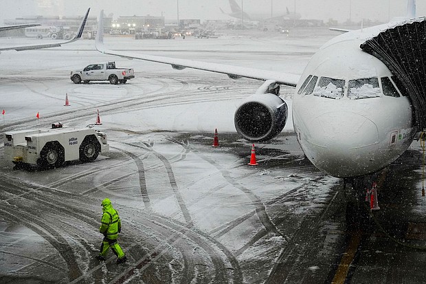 A man walks near a waiting plane as snow falls at John F. Kennedy International Airport in New York on Tuesday.
Mandatory Credit:	Frank Franklin II/AP