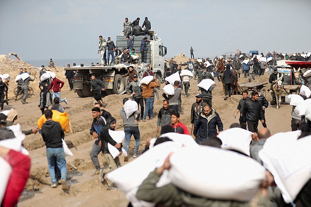 Palestinians carry bags of flour they grabbed from an aid truck near an Israeli checkpoint in Gaza City on February 19.
Mandatory Credit:	Kosay Al Nemer/Reuters via CNN Newsource