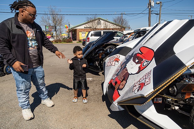 DeAndre Smith and his son, Nuri Harris, 3, take a look at some of the Sling Shots from visiting riders attending the ribbon-cutting ceremony on the lot of Hot Wheelz Sling Shot Rentals.