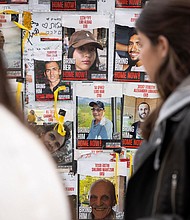 Pedestrians walk past posters of missing Israelis, including rescued hostage Louis Har (center, in blue shirt), on a wall at Hostages Square in Tel Aviv on February 12.
Mandatory Credit:	Oren Ziv/AFP/Getty Images via CNN Newsource