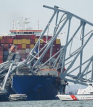 A Coast Guard cutter passes a cargo ship that is stuck under part of the structure of the Francis Scott Key Bridge after the ship hit the bridge Tuesday, March 26, in Baltimore, Maryland.
Mandatory Credit:	Steve Helber/AP via CNN Newsource