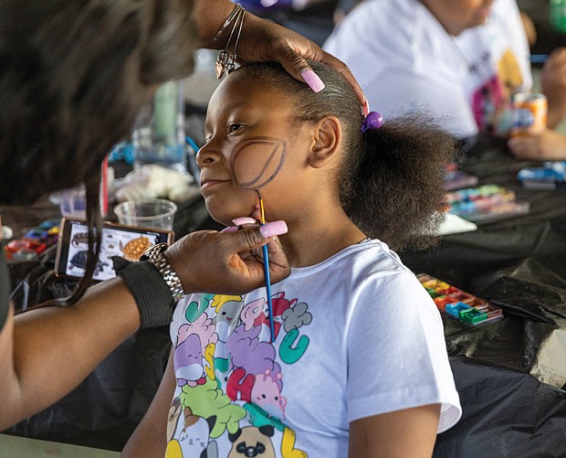 Tamira, 10, gets her face painted at the COLOR Carnival at Bryan Park The event, held across Virginia, offers family activities and resources, including community baby showers. Created by Kenda Sutton-el in 2019 during Black Maternal Health Week, the carnival aims to entertain children while educating mothers about maternal mortality.
