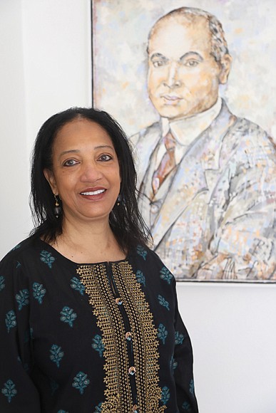 Zarina Fazaldin poses for a portrait in the home that she bought, restored and now celebrates at 508 St. James St., in Historic Jackson Ward. The home originally was commissioned in 1915 for Dr. William Henry Hughes, pictured in a painting behind her, by Black architect Charles T. Russell.