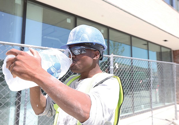 Construction worker Jacob Oliver of Chester takes a break from his work building a new apartment project in Scott’s Addition. Mr. Oliver has been working on the job for a month and acknowledges that the heat can make his job tough.