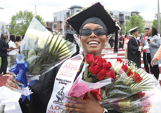 Zakyia Armstrong, 26, of Suffolk, Va., a first generation graduate with a degree in biology, celebrates with bunches of flowers given to her following the graduation.