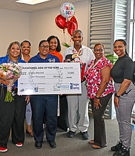 Academic and Behavior East staff surround Angela Mitchell (holding check) for photos. Campus staff joined HCDE leaders in a surprise ceremony for Mitchell, who was named HCDE’s Educational Aide of the Year.