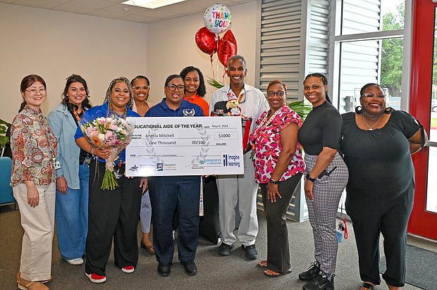 Academic and Behavior East staff surround Angela Mitchell (holding check) for photos. Campus staff joined HCDE leaders in a surprise ceremony for Mitchell, who was named HCDE’s Educational Aide of the Year.