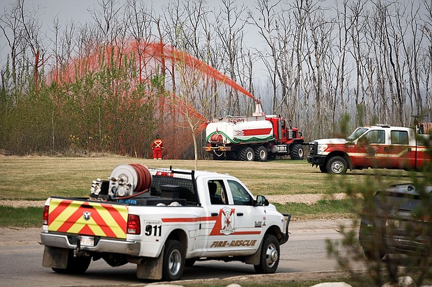 A pumper truck sprays fire retardant on trees around the evacuated neighborhood of Beacon Hill in Fort McMurray, Alberta, Canada, on May 15.
Mandatory Credit:	Jeff McIntosh/The Canadian Press/AP via CNN Newsource