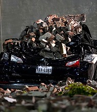 A car crushed by bricks from a fallen building wall sits in a downtown parking lot after a severe thunderstorm passed through Thursday in Houston.
Mandatory Credit:	David J. Phillip/AP via CNN Newsource