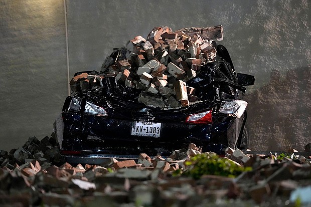 A car crushed by bricks from a fallen building wall sits in a downtown parking lot after a severe thunderstorm passed through Thursday in Houston.
Mandatory Credit:	David J. Phillip/AP via CNN Newsource