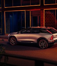 Rear side view of 2025 Cadillac OPTIQ in Argent Silver Metallic with 21-inch alloy wheels.