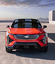 Head-on view of 2025 Cadillac OPTIQ in Monarch Orange, featuring Cadillac vertical lighting signature, sleek LED headlamps and the black crystal shield grille design.