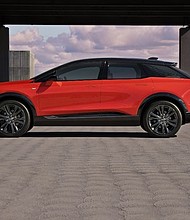 Side profile view of 2025 Cadillac OPTIQ in Monarch Orange.