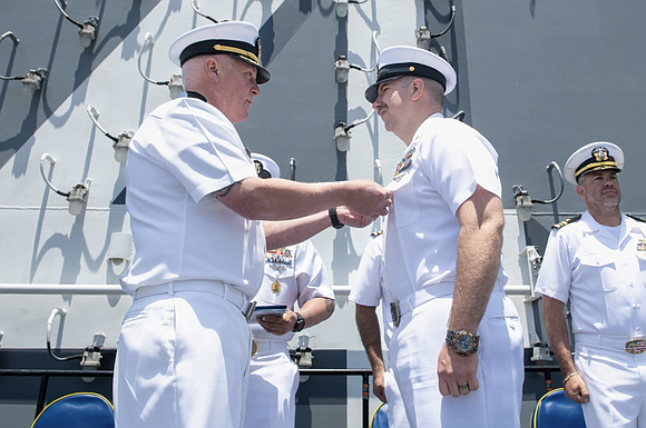 Capt. Jason Tumlinson, left, USS Boxer (LHD 4) executive officer, and a native of Spokane, Washington, presents the Navy and …