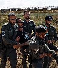 Israeli security forces apprehend a protester from the Tsav 9 movement as the group performs a sit-in in an attempt to block aid shipments from getting into Gaza, in Kerem Shalom, Israel, on March 7.
Mandatory Credit:	Marcus Yam/Los Angeles Times/Getty Images via CNN Newsource