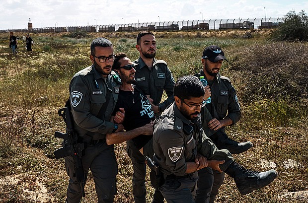 Israeli security forces apprehend a protester from the Tsav 9 movement as the group performs a sit-in in an attempt to block aid shipments from getting into Gaza, in Kerem Shalom, Israel, on March 7.
Mandatory Credit:	Marcus Yam/Los Angeles Times/Getty Images via CNN Newsource