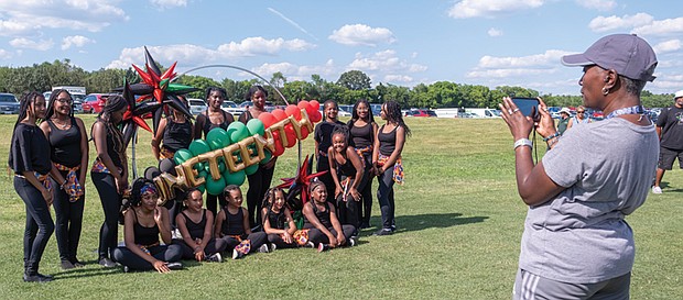 Deborah Walker takes a photograph of The Henrico PAL Dance Team near the Juneteenth sign at Henrico's annual Juneteenth celebration June 15 in Dorey Park.