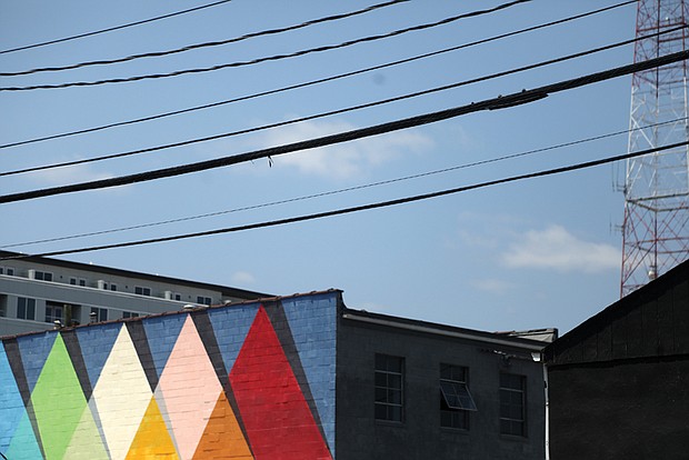 A vibrant mural featuring triangles adorns the Robert B. Moss Theatre, home to Richmond
Triangle Players, at 1300 Altamont Ave. in Scott’s Addition. The colorful geometric design in-
terplays with the urban landscape, merging with power lines, window frames and a TV antenna.
The Pride-inspired triangles pay homage to eight decades of LGBTQ history, echoing the theatre
company’s name and logo.