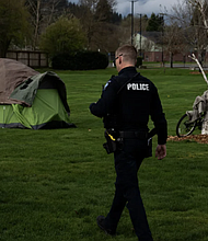 A police officer walks to check on a homeless personon Saturday, March 23, 2024, in Grants Pass, Oregon. Jenny Kane/AP