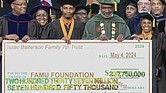 This screen grab provided by WCTV shows Gregory Gerami, a 30-year-old who calls himself Texas’ “youngest African American industrial hemp producer,” third from left, and Florida A&M University president Larry Robinson, posing with a ceremonial check during a commencement ceremony May 4 in Tallahassee, Fla. Robinson announced Friday, July 12, he’s resigning amid backlash over the university’s apparent failure to properly vet the donation.