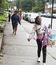 An excited Cynthia Matthews, a fourth-grader at Woodville Elementary School, arrives for her first day back Monday as a part of the RPS200 program. She is steps ahead of her mother, Angelica Blackman, who brought her to school.