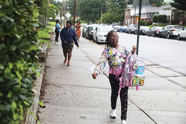 An excited Cynthia Matthews, a fourth-grader at Woodville Elementary School, arrives for her first day back Monday as a part of the RPS200 program. She is steps ahead of her mother, Angelica Blackman, who brought her to school.