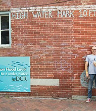Two visitors measure up to Hurricane Gaston’s 2004 high water mark.