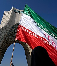 An Iranian flag is carried under the Azadi (Freedom) monument tower during the annual rally commemorating Iran's 1979 Islamic Revolution in Tehran in February.
Mandatory Credit:	Vahid Salemi/AP/File via CNN Newsource