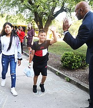 Delegate Michael J. Jones welcomes G.H. Reid Elementary School students with a high-five Monday as they arrive for their first day of school.