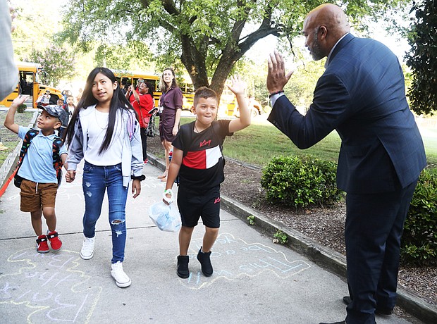 Delegate Michael J. Jones welcomes G.H. Reid Elementary School students with a high-five Monday as they arrive for their first day of school.