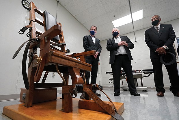 Former Virginia Gov. Ralph Northam, left, looks over the electric chair in the death chamber at Greensville Correctional Center with Operations Director George Hinkle, center, and Warden Larry Edmonds, right, prior to signing a bill on March 24, 2021, abolishing the death penalty in the state.