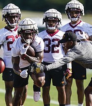 Washington Commanders running back Brian Robinson, second from left, wears a Guardian cap during practice at the team’s training facility July 27, 2022 in Ashburn, Va.
The NFL says it will allow players to wear protective soft-shell helmet covers known as Guardian caps during games if they choose.