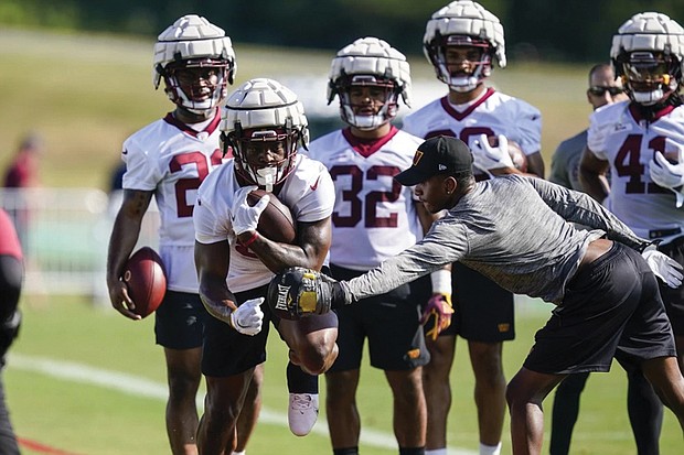 Washington Commanders running back Brian Robinson, second from left, wears a Guardian cap during practice at the team’s training facility July 27, 2022 in Ashburn, Va.
The NFL says it will allow players to wear protective soft-shell helmet covers known as Guardian caps during games if they choose.