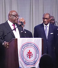 The Rev. Boise Kimber, at podium, president-elect of NBCUSA, addresses the close of the National Baptist Convention, USA annual meeting Sept. 5 at the Baltimore Convention Center in Baltimore. The Rev. Jerry Young, center right, outgoing NBCUSA president, listens to Kimber.