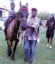 Corey Wilson of Richmond, right, walks alongside his 4-year-old son, also named Corey Wilson, as Donald Fells guides the horse Thunderstorm during the 21st Annual Happily Natural Day on Saturday, Aug. 31, at the 5th District Mini Farm. The event also featured music, vendors and speakers.