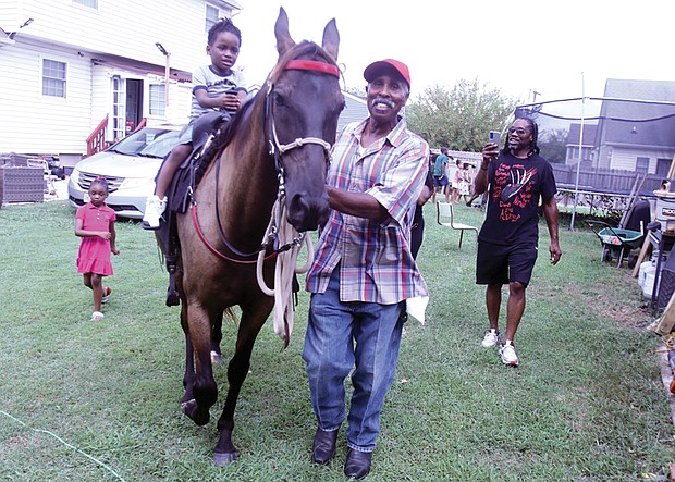 Corey Wilson of Richmond, right, walks alongside his 4-year-old son, also named Corey Wilson, as Donald Fells guides the horse Thunderstorm during the 21st Annual Happily Natural Day on Saturday, Aug. 31, at the 5th District Mini Farm. The event also featured music, vendors and speakers.