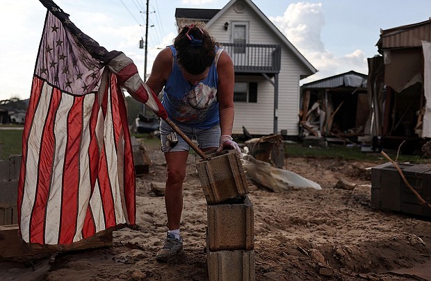 Roxanne Brooks mounts an American flag to a stack of cinderblocks outside her friend's destroyed mobile home (R) in the aftermath of Hurricane Helene flooding on October 6 in Swannanoa, North Carolina.
Mandatory Credit:	Mario Tama/Getty Images via CNN Newsource