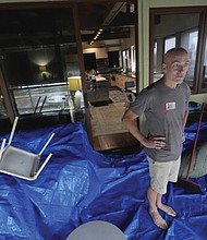 Christian Burke stands on the third floor of his home, where he, his mother, and his aunt plan to ride out Hurricane Milton with views through hurricane proof glass over Tampa Bay, in Gulfport, Fla. Burke, who said his engineer father built the concrete home to withstand a Category 5 hurricane, expects his home to turn into an island, with up to 8 feet of water filling the raised first floor.