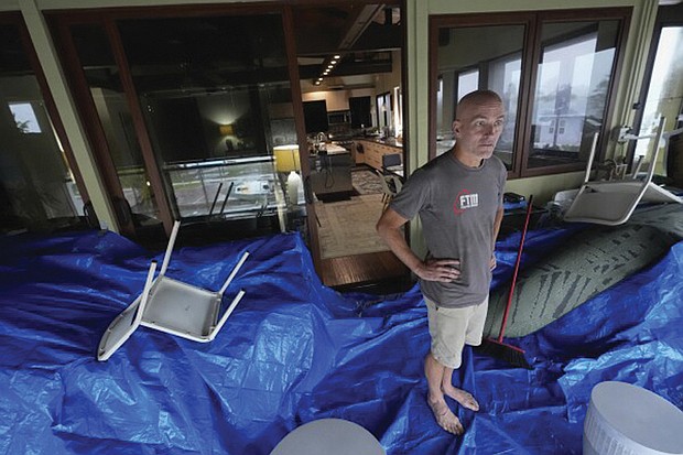 Christian Burke stands on the third floor of his home, where he, his mother, and his aunt plan to ride out Hurricane Milton with views through hurricane proof glass over Tampa Bay, in Gulfport, Fla. Burke, who said his engineer father built the concrete home to withstand a Category 5 hurricane, expects his home to turn into an island, with up to 8 feet of water filling the raised first floor.