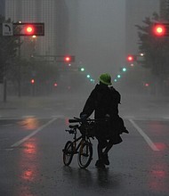 Ron Rook, who said he was looking for people in need of help or debris to clear, walks through windy and rainy conditions Oct. 9 on a deserted street in downtown Tampa, Fla., during the approach of Hurricane Milton.