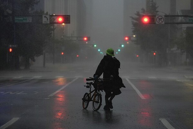 Ron Rook, who said he was looking for people in need of help or debris to clear, walks through windy and rainy conditions Oct. 9 on a deserted street in downtown Tampa, Fla., during the approach of Hurricane Milton.