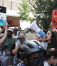 Sereen Haddad, a junior at Virginia Commonwealth University with bullhorn, leads a student-organized walkout on Monday, Oct. 7. The demonstration, marking one year since the start of the Israel-Hamas conflict, saw about 100 participants march from the Monroe Park Campus to the Virginia General Assembly Building on East Broad Street.