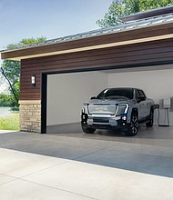 2025 GMC Sierra EV Denali in Thunderstorm Gray charging with GM Energy products inside a garage.