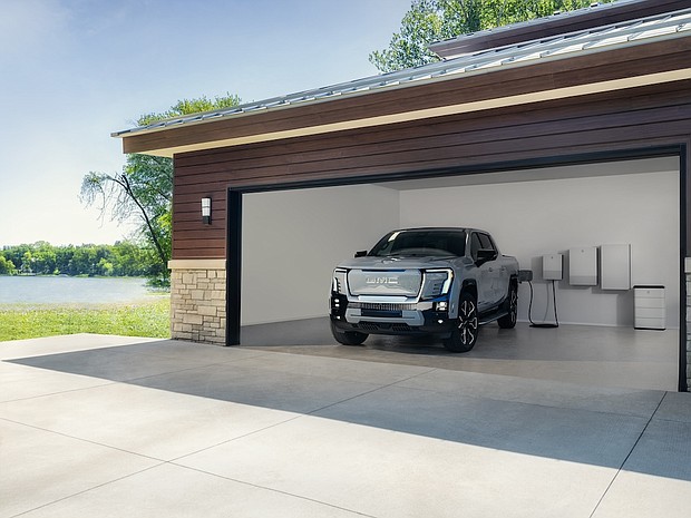 2025 GMC Sierra EV Denali in Thunderstorm Gray charging with GM Energy products inside a garage.