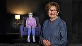 Holocaust survivor Halina Zimm stands next to her interactive image in the Alan and Halina Zimm Theater of Remembrance at the Virginia Holocaust Museum where visitors can engage with her powerful story.